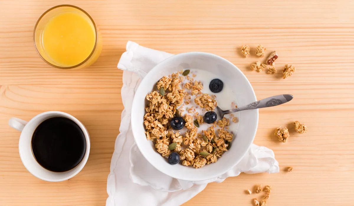 Lait avec du muesli, un verre de jus d'orange et une tasse de café